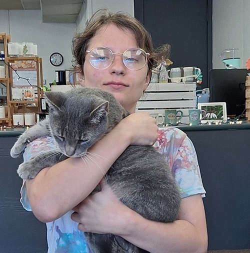 Young woman with tie dyed t-shirt and glasses holding gray cat