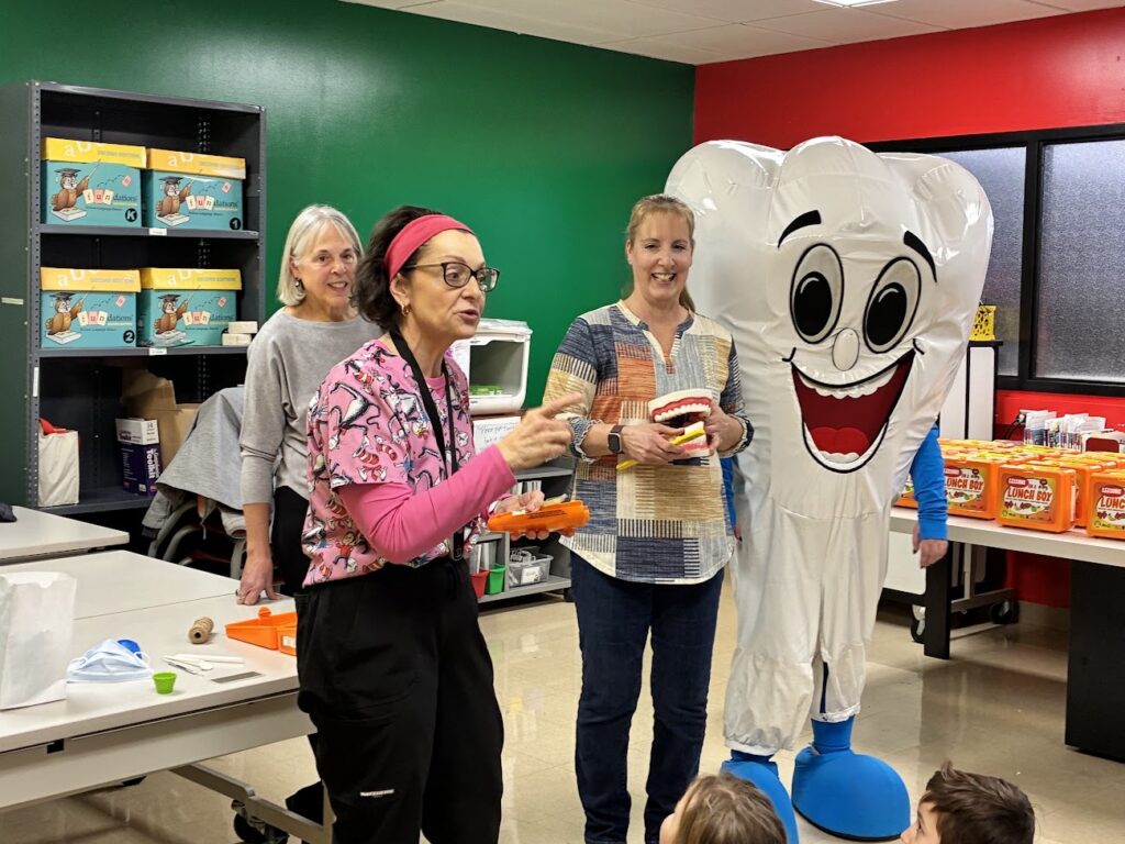 Three dental hygienists teach school kids about brushing.